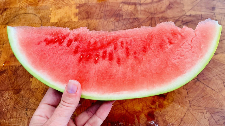 Hand holding large slice of watermelon