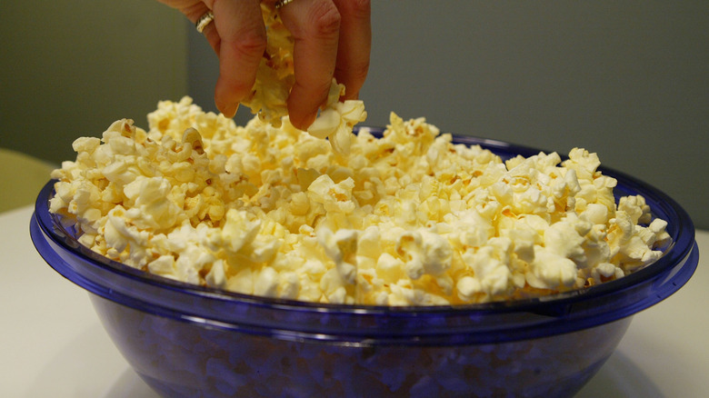Someone reaching into a bowl of microwaved popcorn
