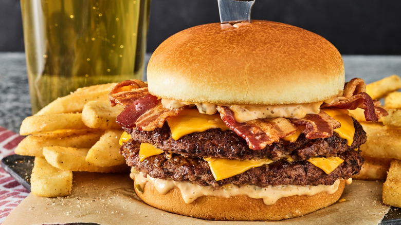 A Red Robin burger is loaded with cheese and bacon and sits amidst seasoned fries