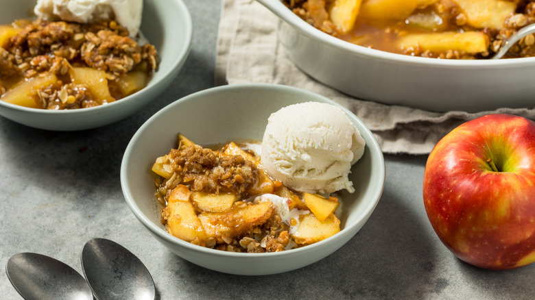 Bowls of apple cobbler with a whole apple beside them