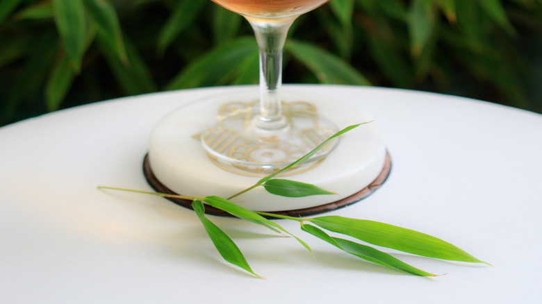 A bamboo cocktail with bamboo leaves behind it