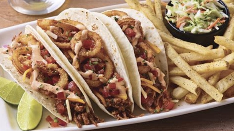 Platter of BBQ Brisket Tacos served with fries, slaw, and lime wedges