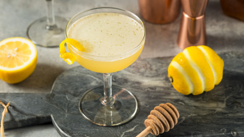 A bees knees cocktail with a lemon and honey spoon