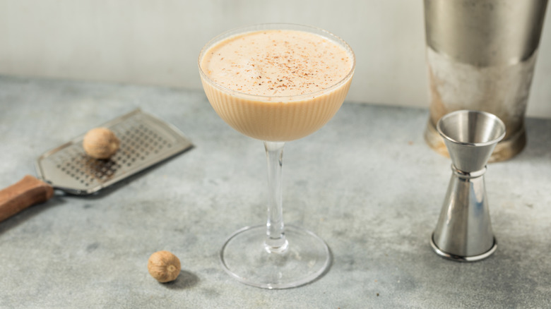 A Brandy Alexander with a grater, nutmeg and jigger beside it