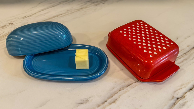two butter dishes on a marble countertop