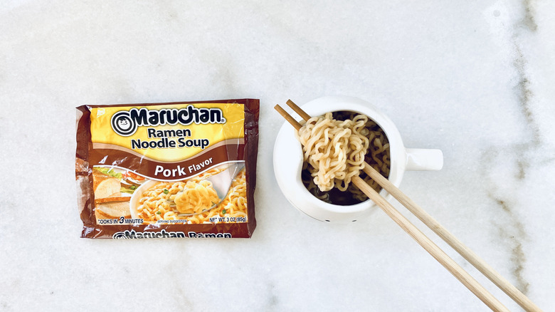 Pack of pork Maruchan ramen next to some in a bowl with chopsticks