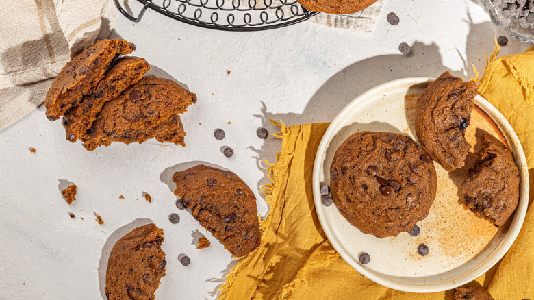 Pumpkin chocolate chip cookies broken into half laying on the table and one plate 