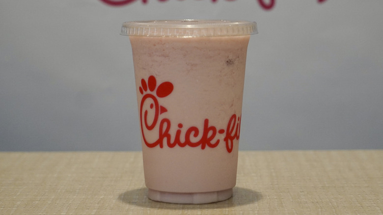 Cherry Berry Frosted Lemonade on a tan table in front of a white Chick-fil-A step and repeat