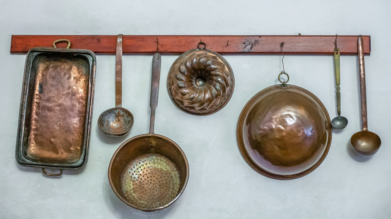 copper molds and utensils hanging on a wall