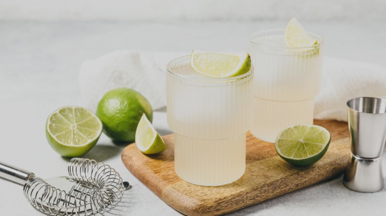 two lime cocktails on a wooden board.