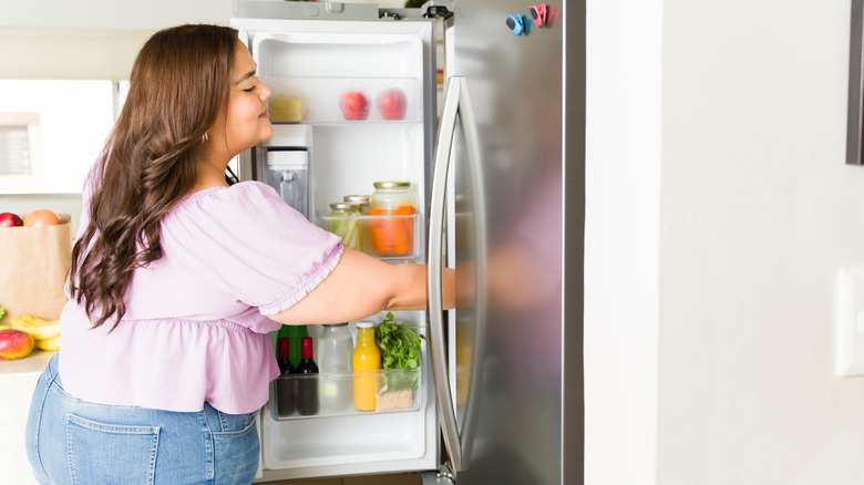 A person opening a fridge with an organized door