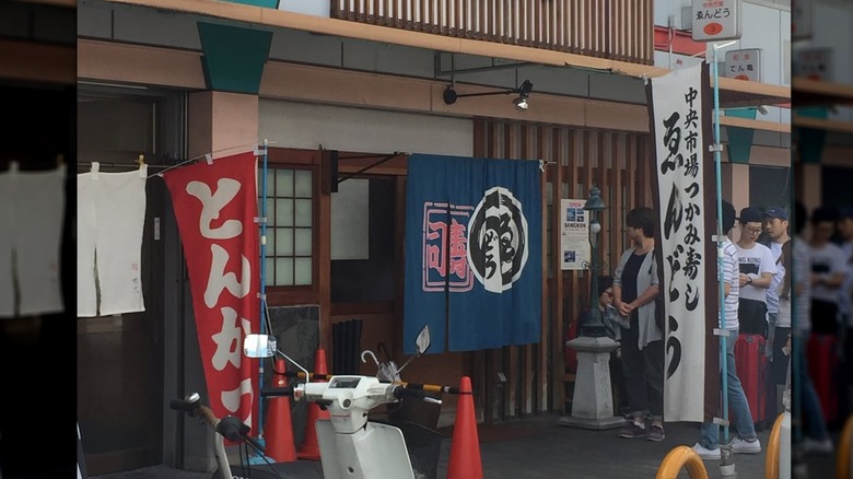 The exterior of Endo Sushi, a few people lined up outside