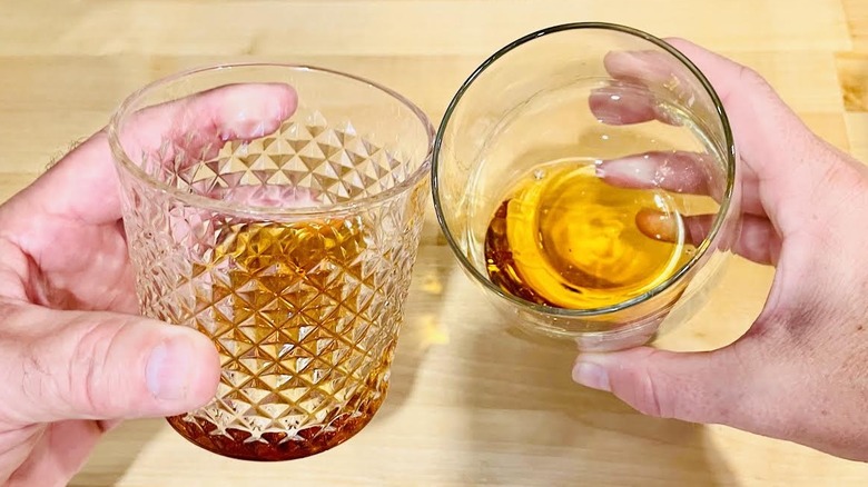 Two hands clinking glasses of Old Forester Birthday Bourbon 2025