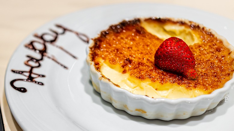Fogo de Chão creme brûlée on a white plate with a strawberry on top
