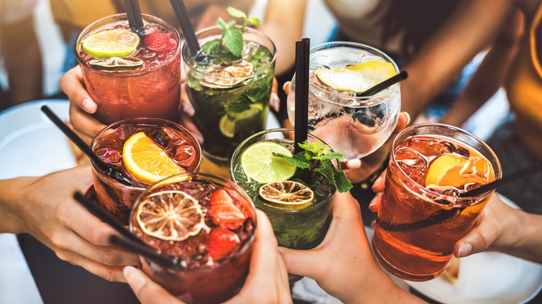 Glasses with colorful drinks being clinked together in a toast