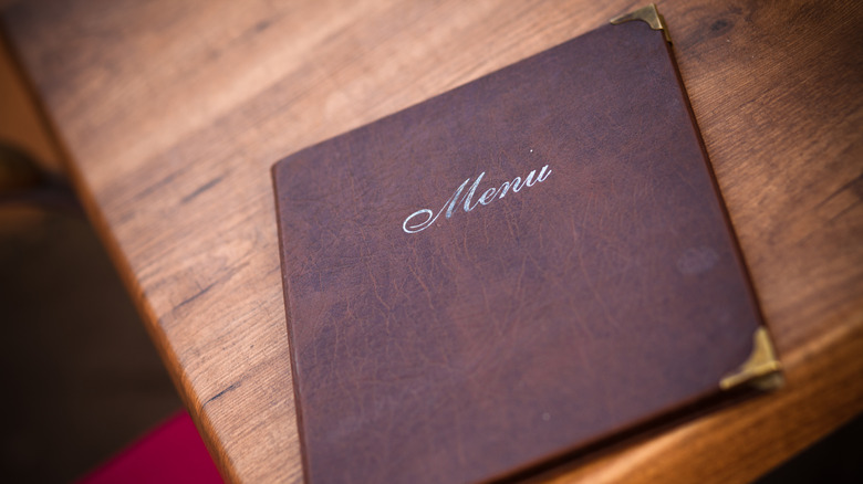 A folding menu sits on a wooden table