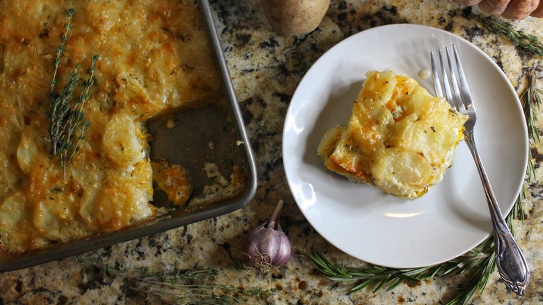 pumpkin potato gratin slice on white plate next to tray
