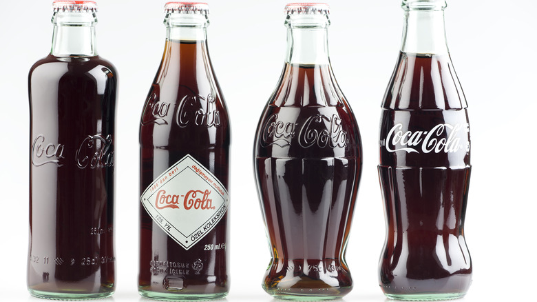 Four vintage Coke bottles, showing the different shapes of the early product