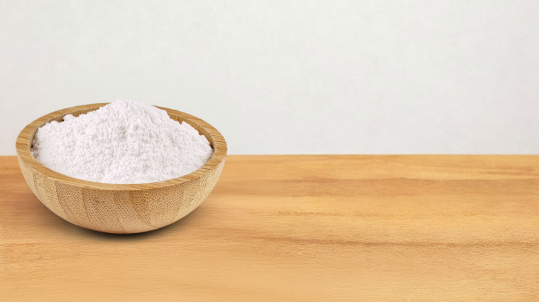 A small wooden bowl of cream of tartar on a wooden table