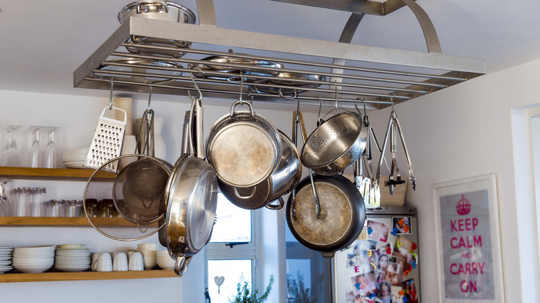 Hanging pot rack with pots, colander, pans, utensils, and grater.