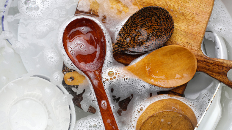 Soapy sink full of wooden utensils
