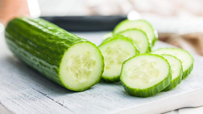 Closeup of sliced cucumber on a white wood table.