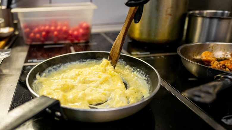 Person scrambling eggs in a pan.