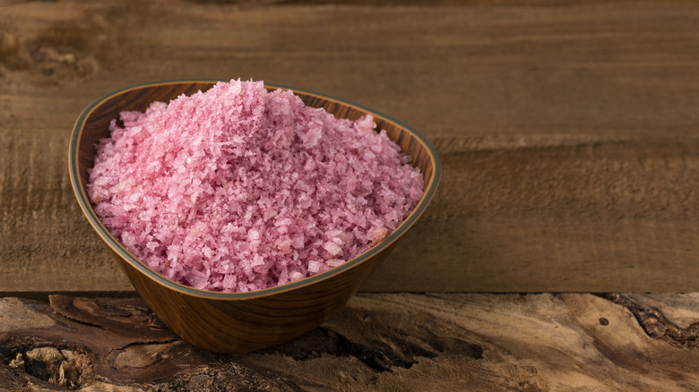 Wooden bowl of red wine salt on a wood table.
