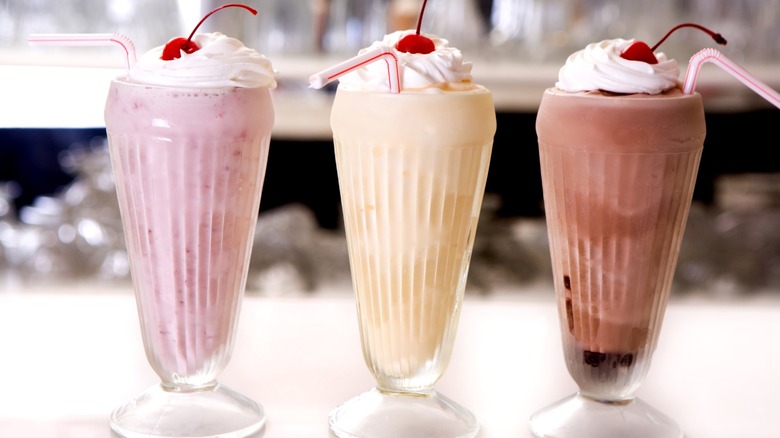 Strawberry, vanilla, and chocolate milkshakes in a row 