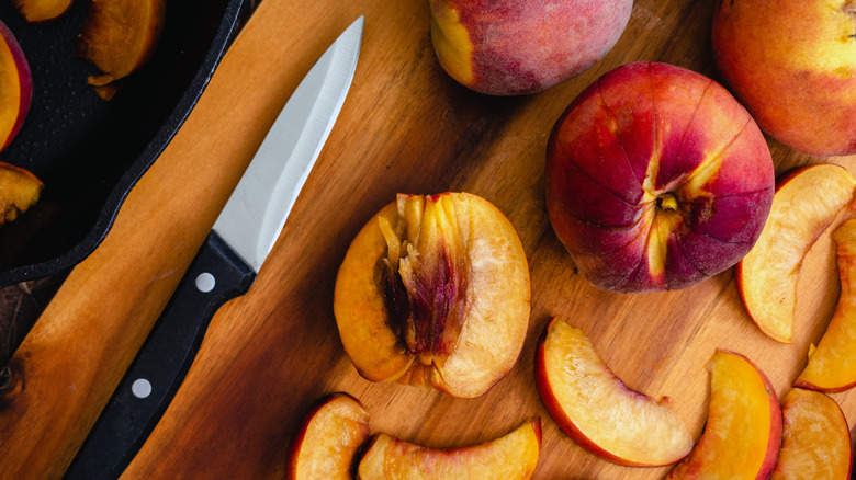 Paring knife on a wooden board with sliced and whole nectarines
