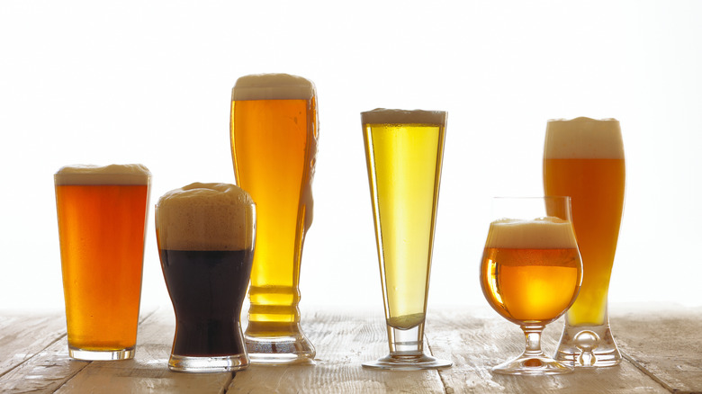 A variety of beers in a variety of glasses sit on a wooden surface