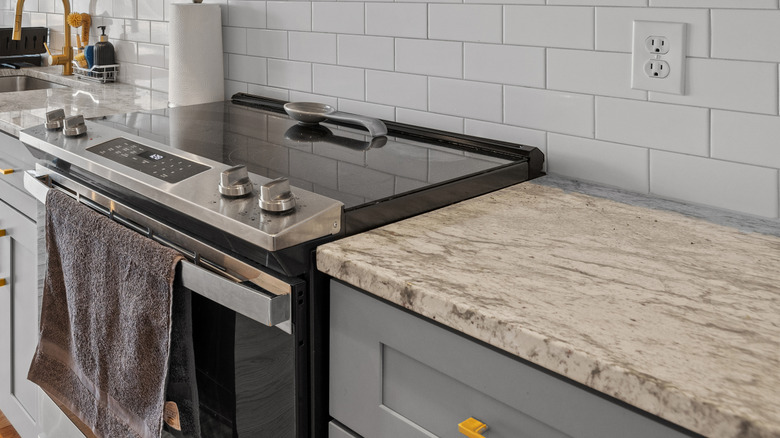A flat top electric stove sits nestled up against a kitchen counter