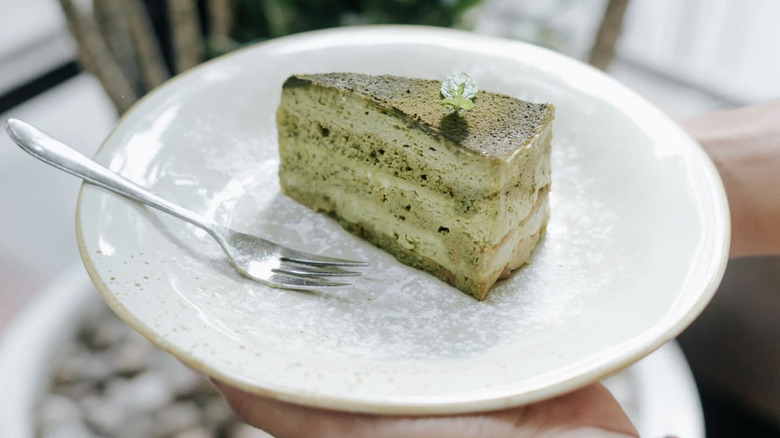 a slice of vibrant green matcha tiramisu on a white plate with a fork