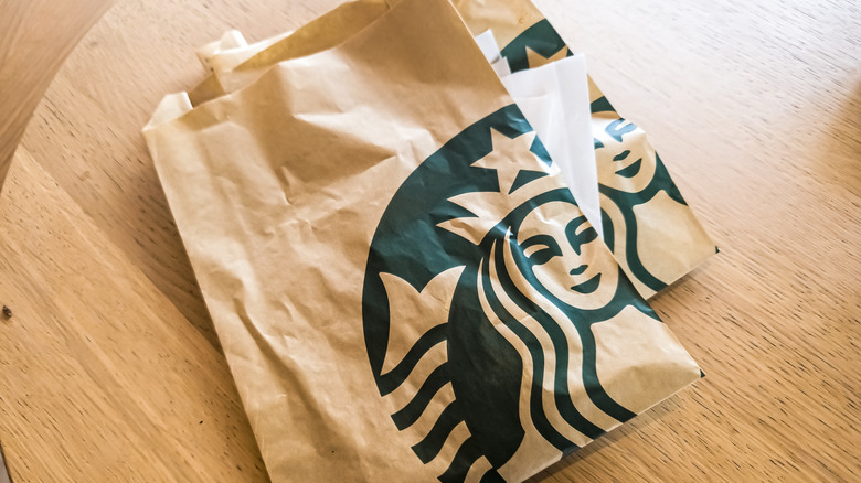 Starbucks logo food bags on table.