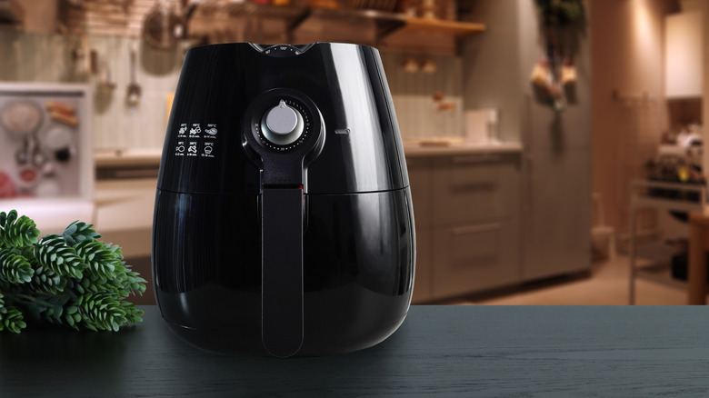 A black air fryer sits on a counter in a kitchen.