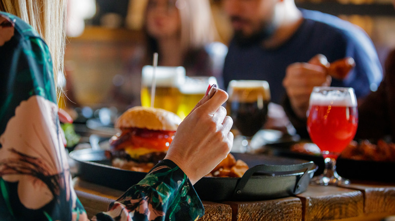 Anonymous diners eat burgers and enjoy cocktails in a restaurant