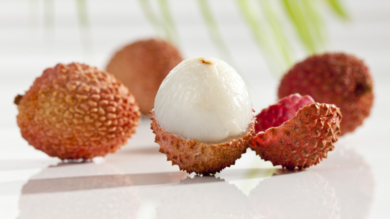 Several fresh lychee fruits with one peeled