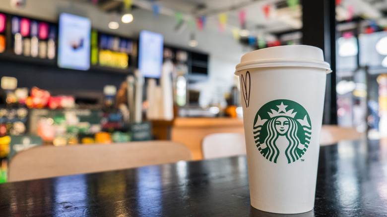 Starbucks drink sits on a table across from the register