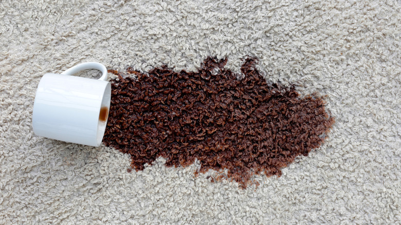 A cup of coffee spilled onto a gray carpet