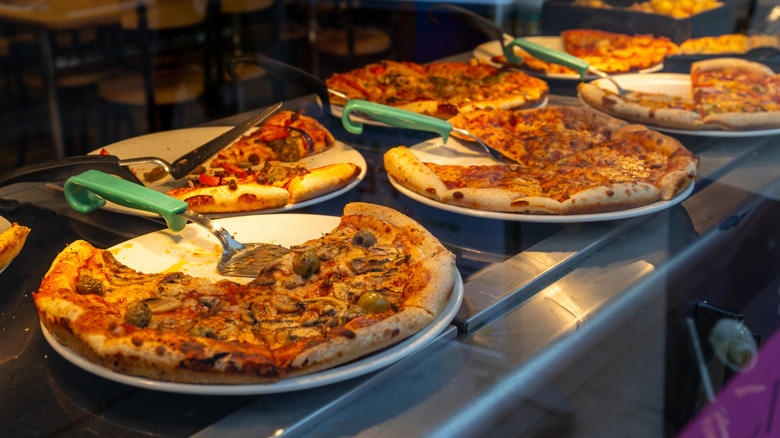 A variety of pizzas wait to be served up at a pizza buffet restaurant