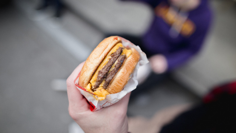 Person holding a double patty fast food burger.