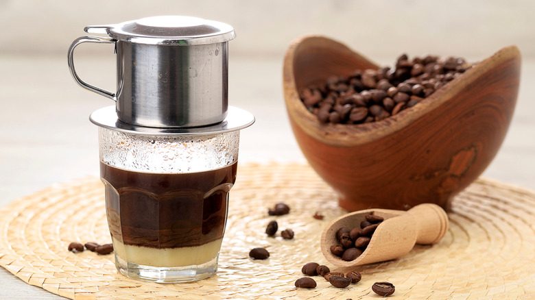 A shot of Vietnamese coffee alongside a bowl of coffee beans