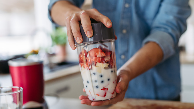 Person making fruit smoothie in a blender