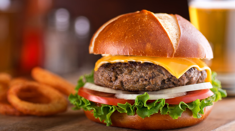 Pretzel bun cheese burger with beer and onion rings