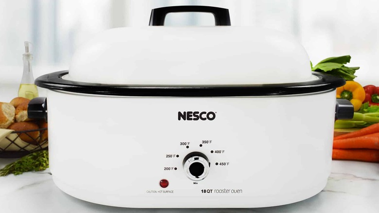 white oven roaster with veggies behind it