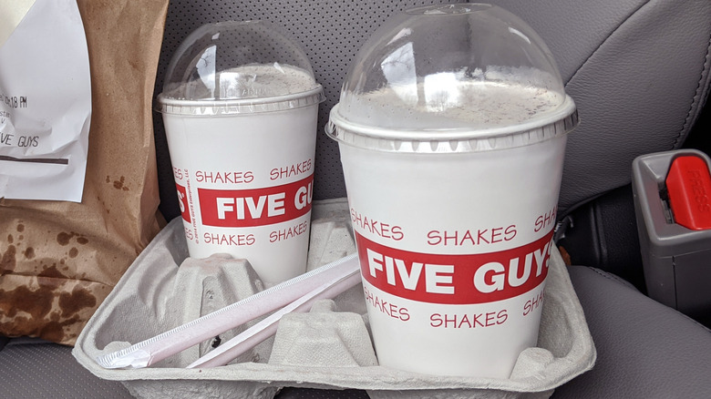 Two Five Guys milkshake in beverage container in car