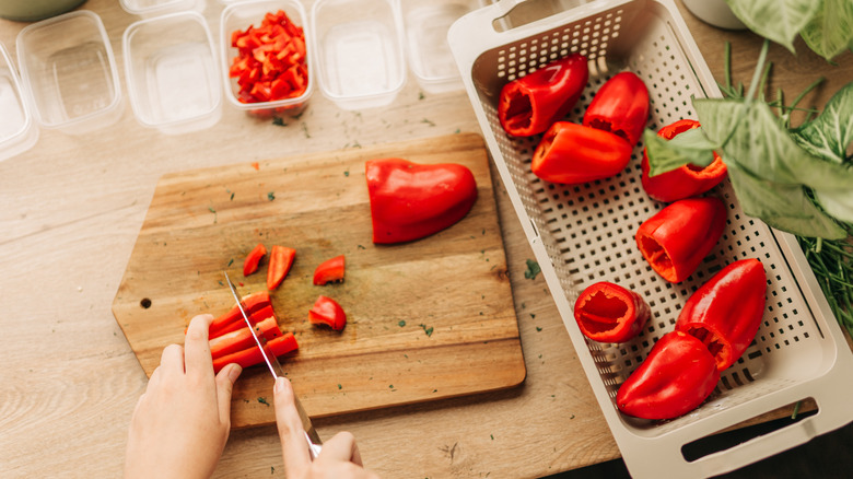 Person chopping red bell peppers