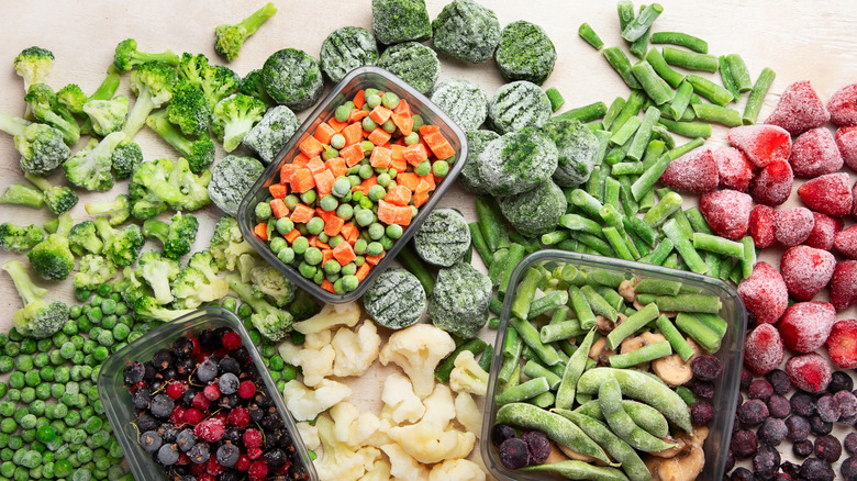 Variety of frozen vegetables and fruit on blank surface.