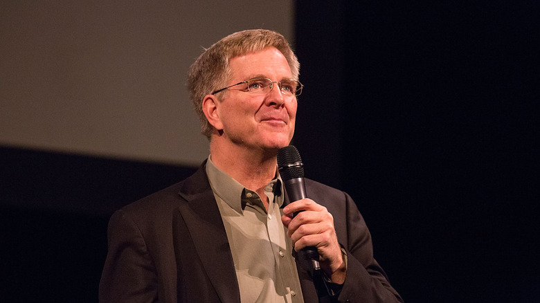 Rick Steves on stage talking into a microphone.