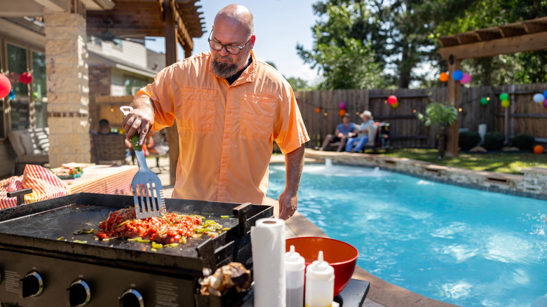 A man grilling meat at a pool party